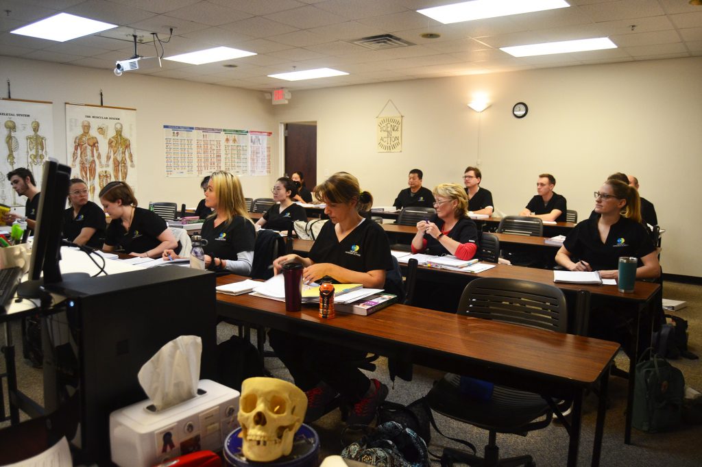 A classroom full of students learning about massage therapy.