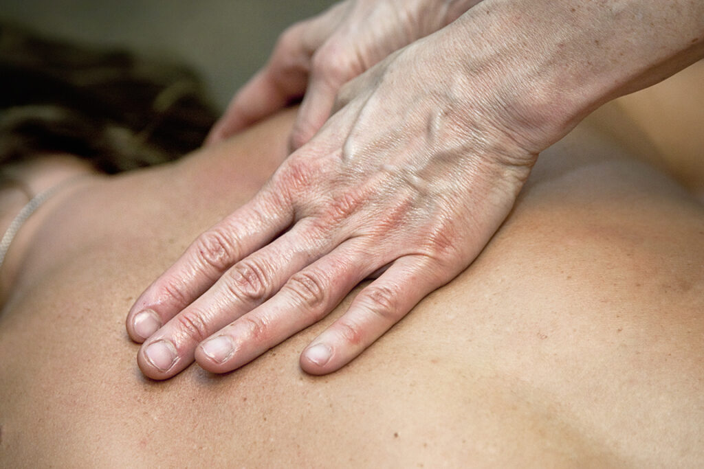 A close-up photo of a pair of hands giving a back massage.